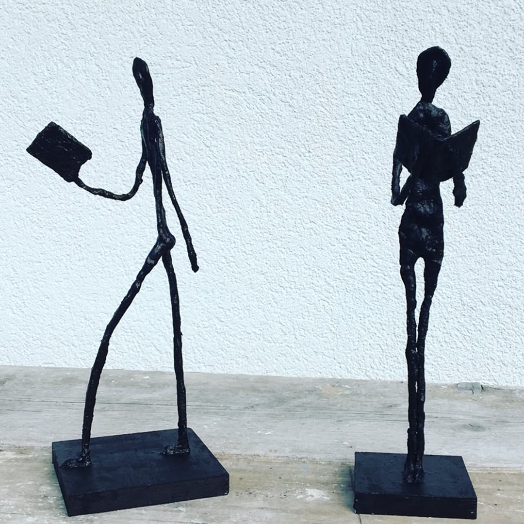 Zwei filigrane Giacometti-Figuren beim Lesen