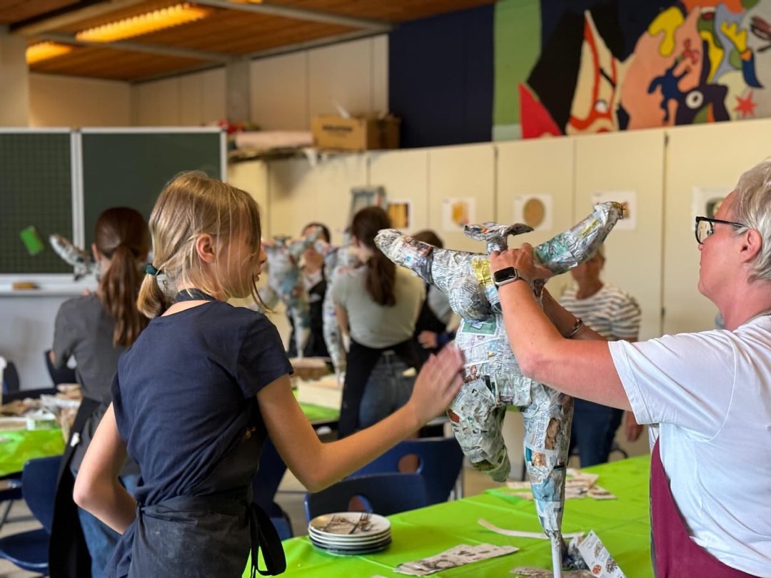Schülerin und Lehrerin bauen gemeinsam eine Nana-Figur aus Zeitungspapier auf