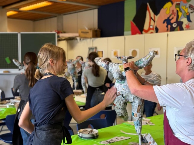 Schülerin und Lehrerin bauen gemeinsam eine Nana-Figur aus Zeitungspapier auf
